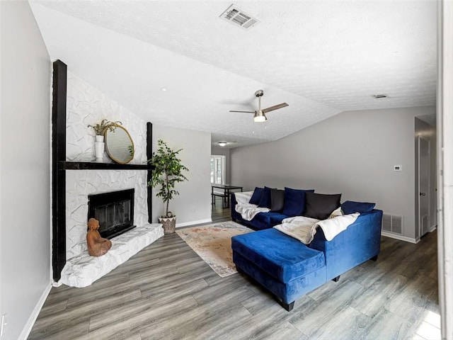 30 Court S, Ellenwood, GA 30294 - living room featuring wood finished floors, vaulted ceiling, ceiling fan, a textured ceiling, and a fireplace