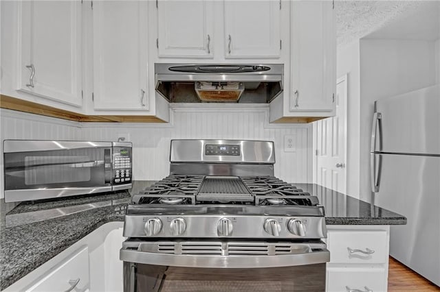 4440 Coventry Ct NE, Roswell, GA 30075 - kitchen with stainless steel appliances, extractor fan, white cabinetry, and dark stone countertops
