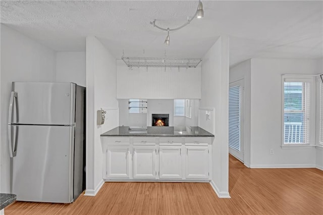4440 Coventry Ct NE, Roswell, GA 30075 - kitchen with freestanding refrigerator, dark countertops, light wood-type flooring, and white cabinets