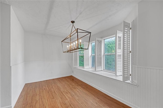 4440 Coventry Ct NE, Roswell, GA 30075 - spare room featuring wood finished floors, wainscoting, a textured ceiling, and a chandelier