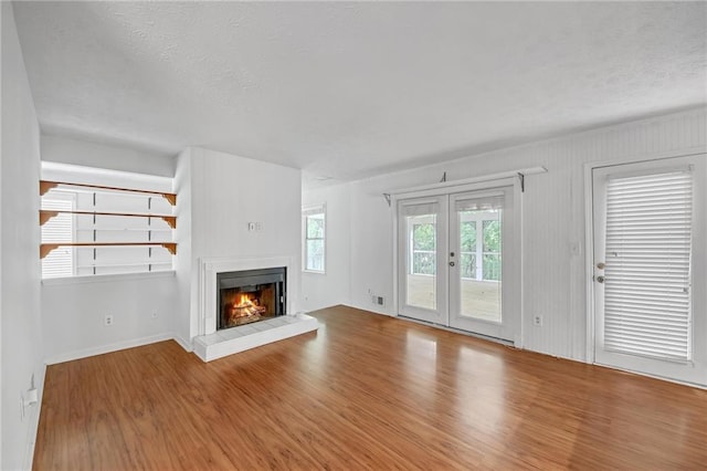 4440 Coventry Ct NE, Roswell, GA 30075 - unfurnished living room with wood finished floors, a glass covered fireplace, french doors, a textured ceiling, and baseboards