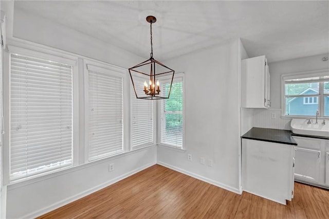 4440 Coventry Ct NE, Roswell, GA 30075 - unfurnished dining area with a chandelier, light wood-type flooring, baseboards, and a sink