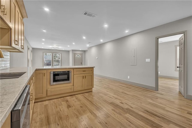 kitchen featuring appliances with stainless steel finishes, light hardwood / wood-style flooring, light brown cabinetry, and kitchen peninsula