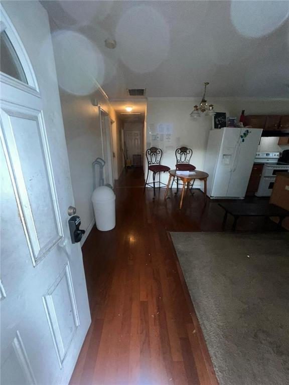 hallway featuring a notable chandelier and dark wood-type flooring