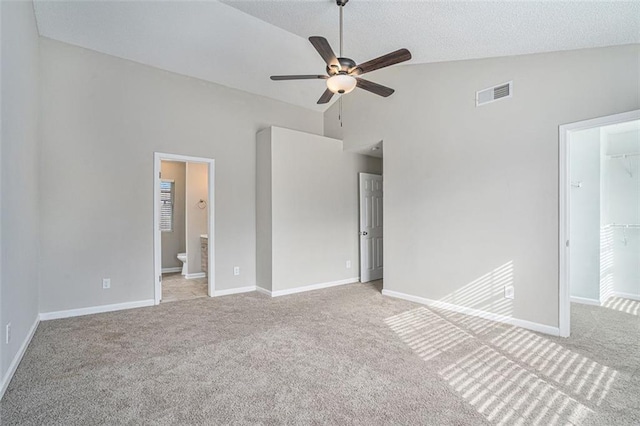 unfurnished bedroom with a spacious closet, a closet, connected bathroom, light colored carpet, and ceiling fan