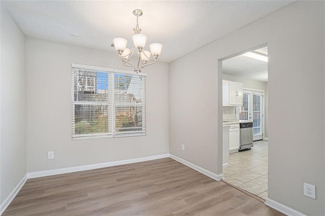 unfurnished dining area featuring a textured ceiling, light hardwood / wood-style flooring, plenty of natural light, and a chandelier