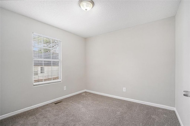 carpeted empty room featuring a textured ceiling