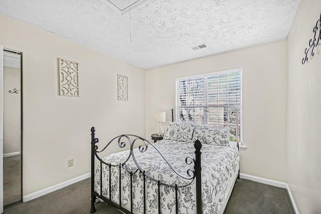 bedroom featuring a textured ceiling and dark colored carpet