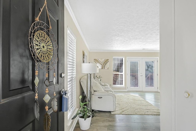 foyer with crown molding, wood-type flooring, a textured ceiling, and french doors