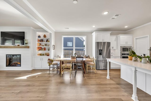 259 Dunagan Ct, Winder, GA 30680 - dining space featuring a fireplace, light wood-style flooring, crown molding, built in features, and recessed lighting