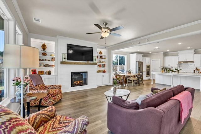 259 Dunagan Ct, Winder, GA 30680 - living room featuring ornamental molding, ceiling fan, light wood-type flooring, and a large fireplace