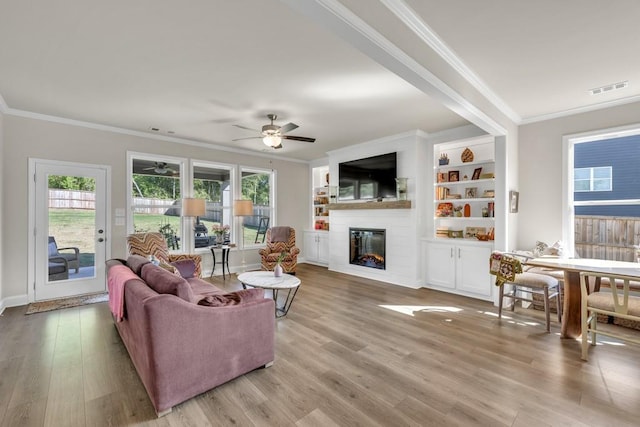 259 Dunagan Ct, Winder, GA 30680 - living room with ceiling fan, ornamental molding, light wood-style floors, and a glass covered fireplace