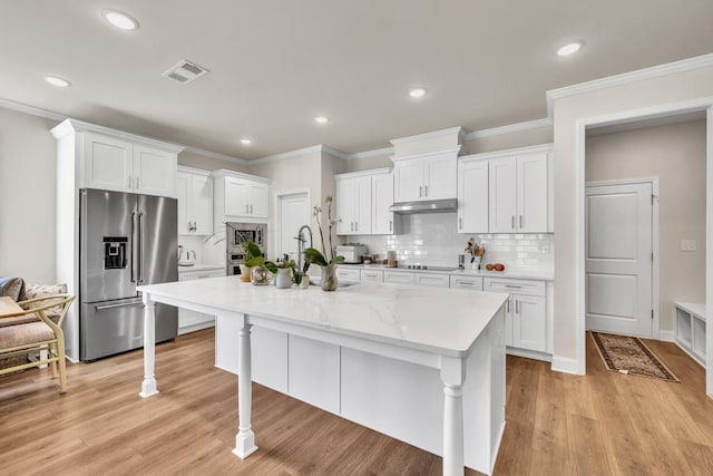 259 Dunagan Ct, Winder, GA 30680 - kitchen with appliances with stainless steel finishes, under cabinet range hood, white cabinets, a breakfast bar area, and a kitchen island with sink