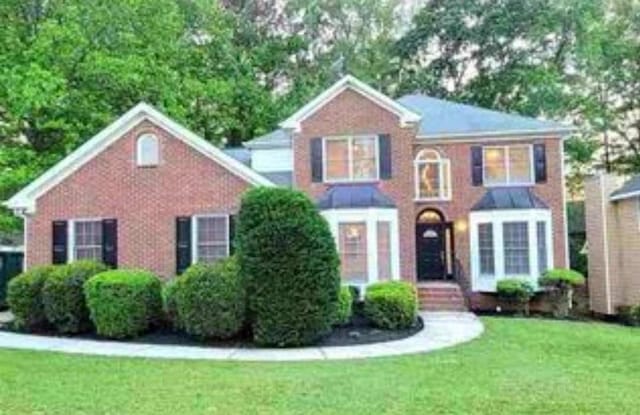 colonial inspired home featuring a front lawn and brick siding