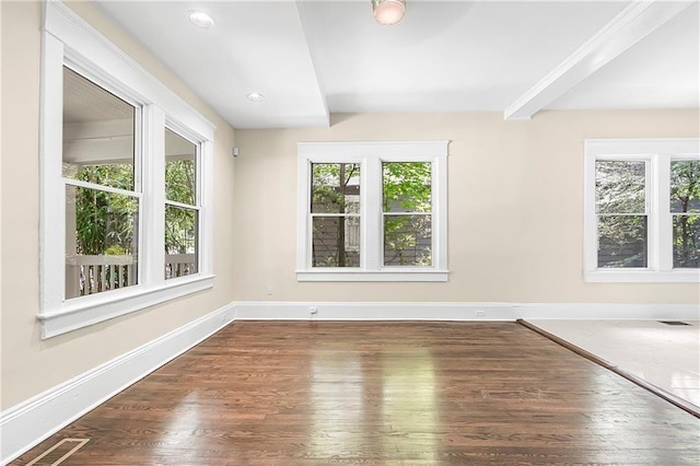 spare room with beam ceiling and dark wood-type flooring