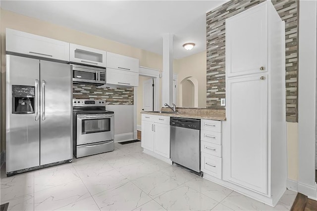 kitchen with decorative backsplash, sink, white cabinets, and stainless steel appliances