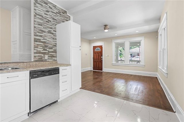 kitchen featuring sink, white cabinetry, stainless steel dishwasher, and light stone counters