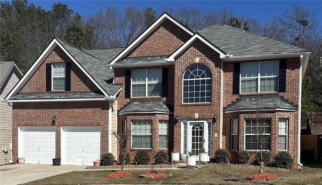 traditional home featuring concrete driveway, an attached garage, and brick siding