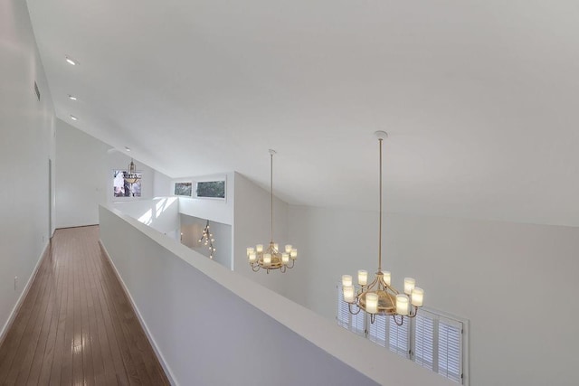 hallway with a notable chandelier, hardwood / wood-style floors, and high vaulted ceiling