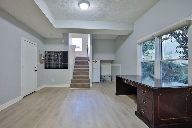 unfurnished office featuring a textured ceiling and light hardwood / wood-style flooring