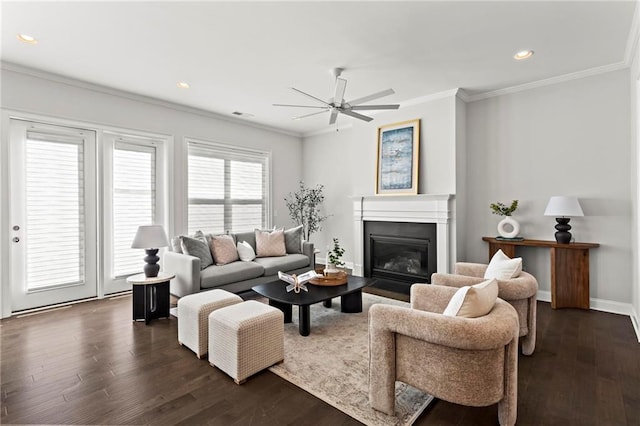 living area with baseboards, ornamental molding, recessed lighting, a glass covered fireplace, and dark wood-style flooring