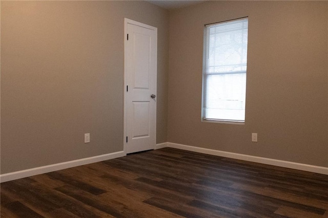 spare room featuring baseboards and dark wood-style flooring