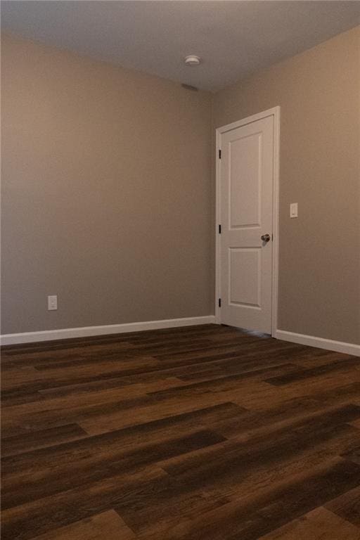 empty room featuring dark wood-type flooring and baseboards