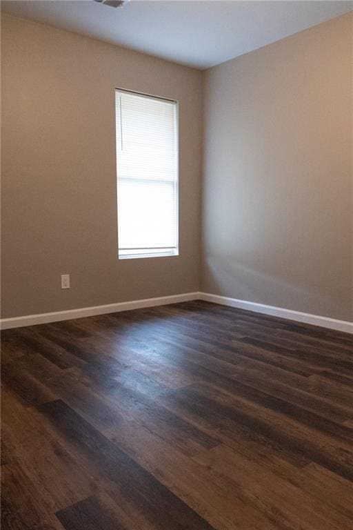 unfurnished room featuring dark wood-style flooring and baseboards