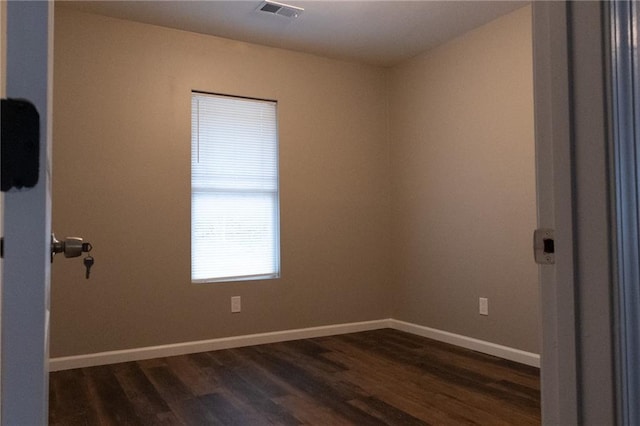 empty room with baseboards, visible vents, and dark wood-style flooring