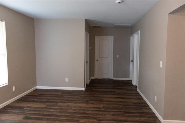 spare room featuring dark wood-style floors, visible vents, and baseboards