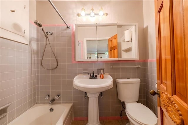 bathroom with tile walls, tiled shower / bath combo, and toilet