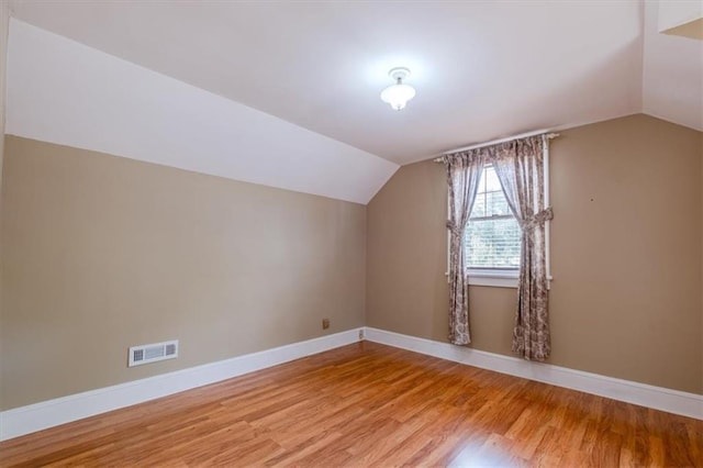 additional living space featuring wood-type flooring and vaulted ceiling