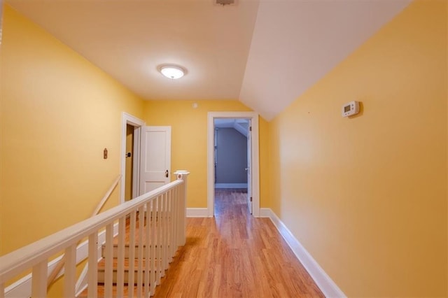 corridor with lofted ceiling and light hardwood / wood-style floors