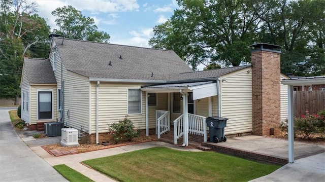 view of front of home featuring a patio area, a front yard, and central air condition unit