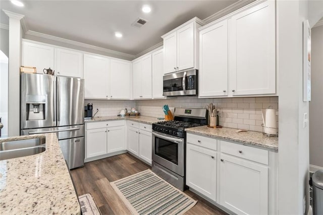 kitchen with dark wood-type flooring, decorative backsplash, visible vents, and stainless steel appliances