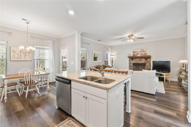 kitchen featuring plenty of natural light, dishwasher, a stone fireplace, a sink, and ceiling fan with notable chandelier