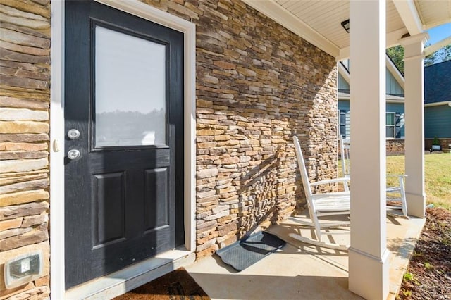 property entrance with stone siding and a porch