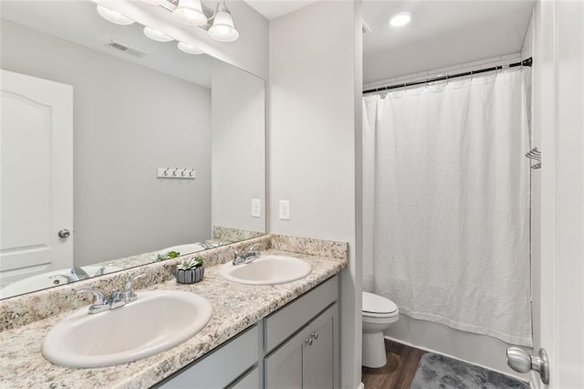 bathroom featuring visible vents, a sink, toilet, and wood finished floors