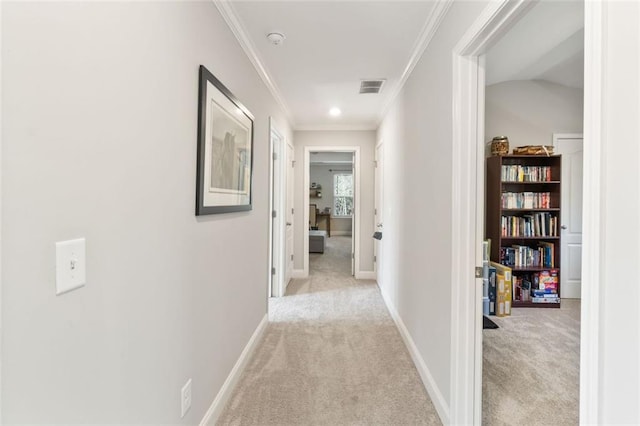 corridor featuring baseboards, ornamental molding, visible vents, and light colored carpet