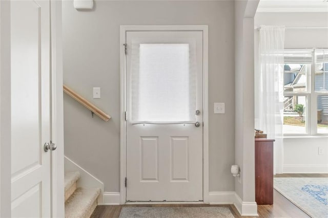 doorway with baseboards, wood finished floors, and stairway