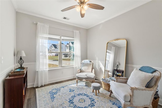 sitting room with ornamental molding, visible vents, a ceiling fan, and wood finished floors