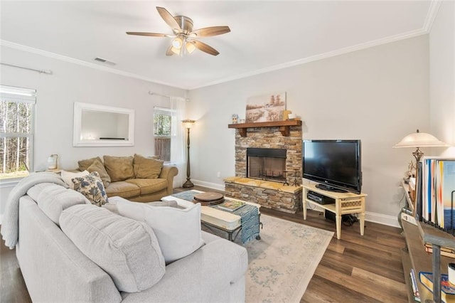 living area with visible vents, crown molding, baseboards, wood finished floors, and a ceiling fan