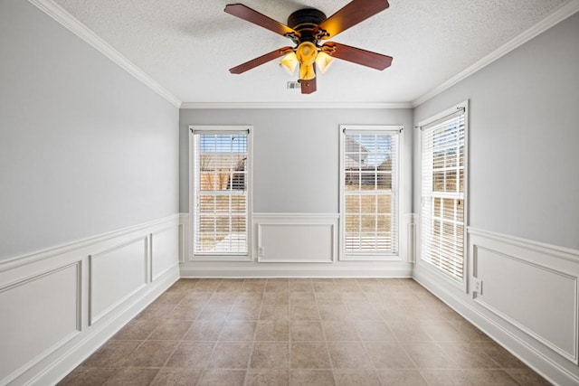 unfurnished room featuring a textured ceiling, wainscoting, visible vents, and crown molding