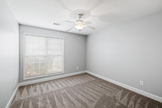 carpeted spare room with a ceiling fan, visible vents, a textured ceiling, and baseboards