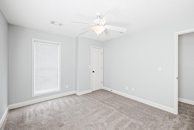 carpeted spare room with ceiling fan, visible vents, and baseboards