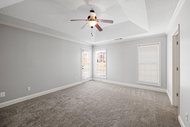 empty room with carpet floors, crown molding, a raised ceiling, visible vents, and a textured ceiling