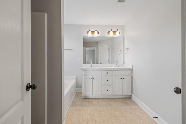 bathroom with double vanity, a sink, a tub, and baseboards