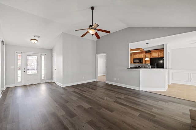 unfurnished living room featuring vaulted ceiling, dark wood finished floors, visible vents, and a ceiling fan