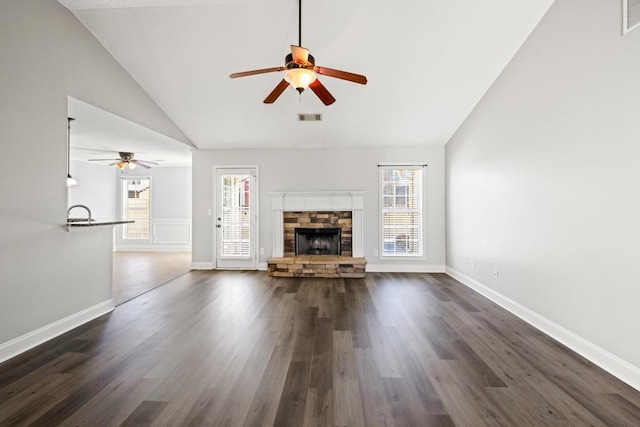 unfurnished living room featuring dark wood-style floors, visible vents, a stone fireplace, and baseboards