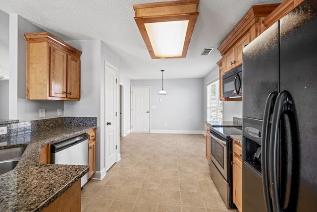 kitchen with black appliances, brown cabinetry, dark stone countertops, and visible vents